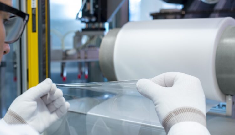 Elongation of a transparent, ultra-thin plastic film pulled from a roll.